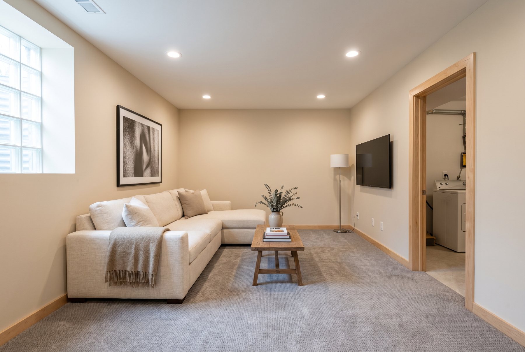 Minimally styled finished basement family room with a sectional sofa, framed print and recessed lighting