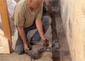 Worker uses drill to waterproof basement